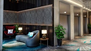 A modern lobby with a curved sofa, a red chair, a small table with a lamp, and a potted plant. - Louis Kienne Hotel Simpang Lima (Semarang)