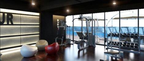 A modern gym with exercise equipment, a large window, and a wooden floor.