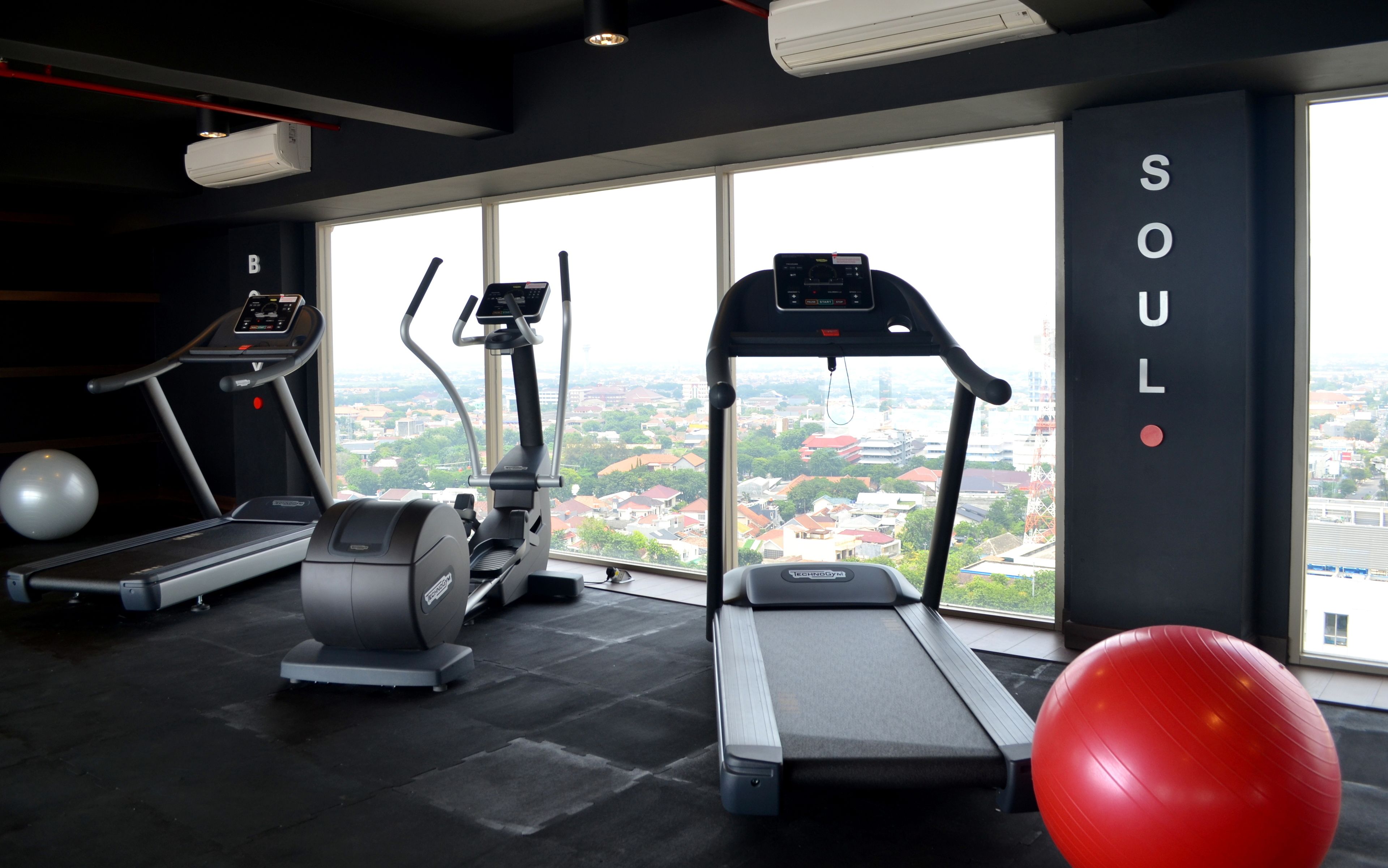A gym with treadmills, elliptical machines, and a red exercise ball.