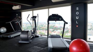 A gym with treadmills, elliptical machines, and a red exercise ball.
