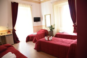 Three beds, flat-screen TV, and a large mirror adorn this stylish room.