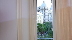 A window with a view of a cityscape, including a large building with a dome and several smaller buildings. - B&B The Queens (Foggia)