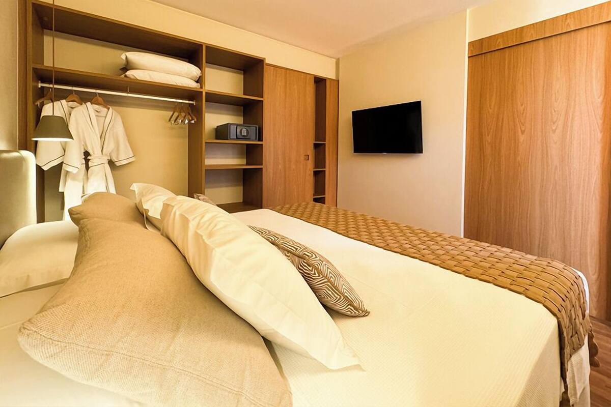 Ein Hotelzimmer mit einem Bett, einem Kleiderschrank, einem Fernseher und einem Nachttisch.