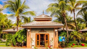 A traditional building with a tiled roof, a central entrance, and a sign indicating a spa. -  Hot Beach Raízes (Olímpia)
