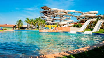 Experience the thrill of a multi-level water slide structure surrounded by a spacious deck area amidst lush palm trees.