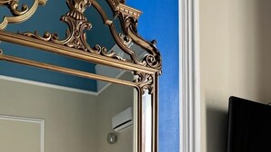 A bathroom with a large ornate mirror, a potted plant with pink tulips, and a blue wall. - Bellini Home B&B (Catania)