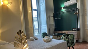 A hotel room with a bed, a chair, a table, and a TV. - Bellini Home B&B (Catania)