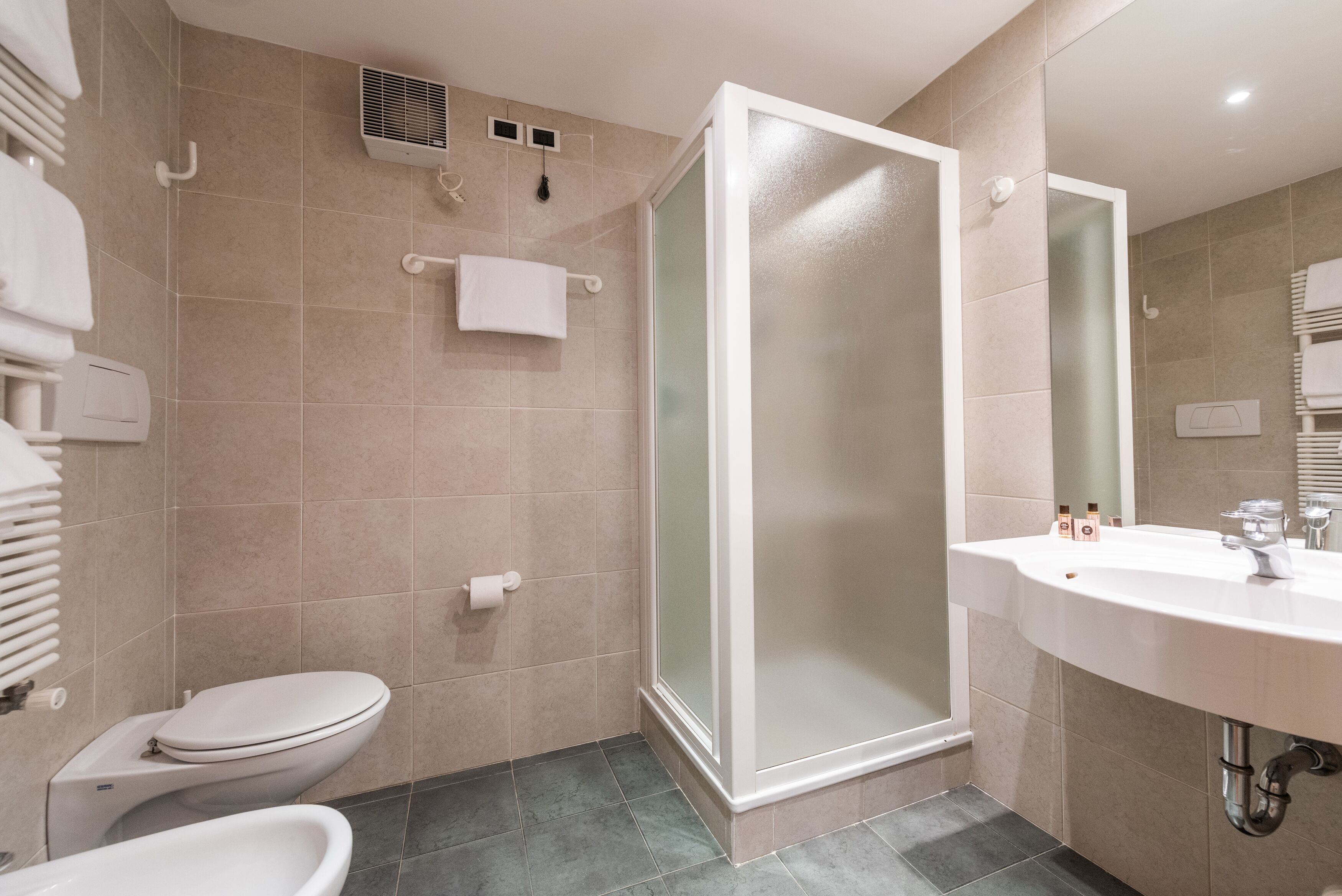 Un baño moderno con inodoro, bidé y ducha con cerramiento de vidrio.