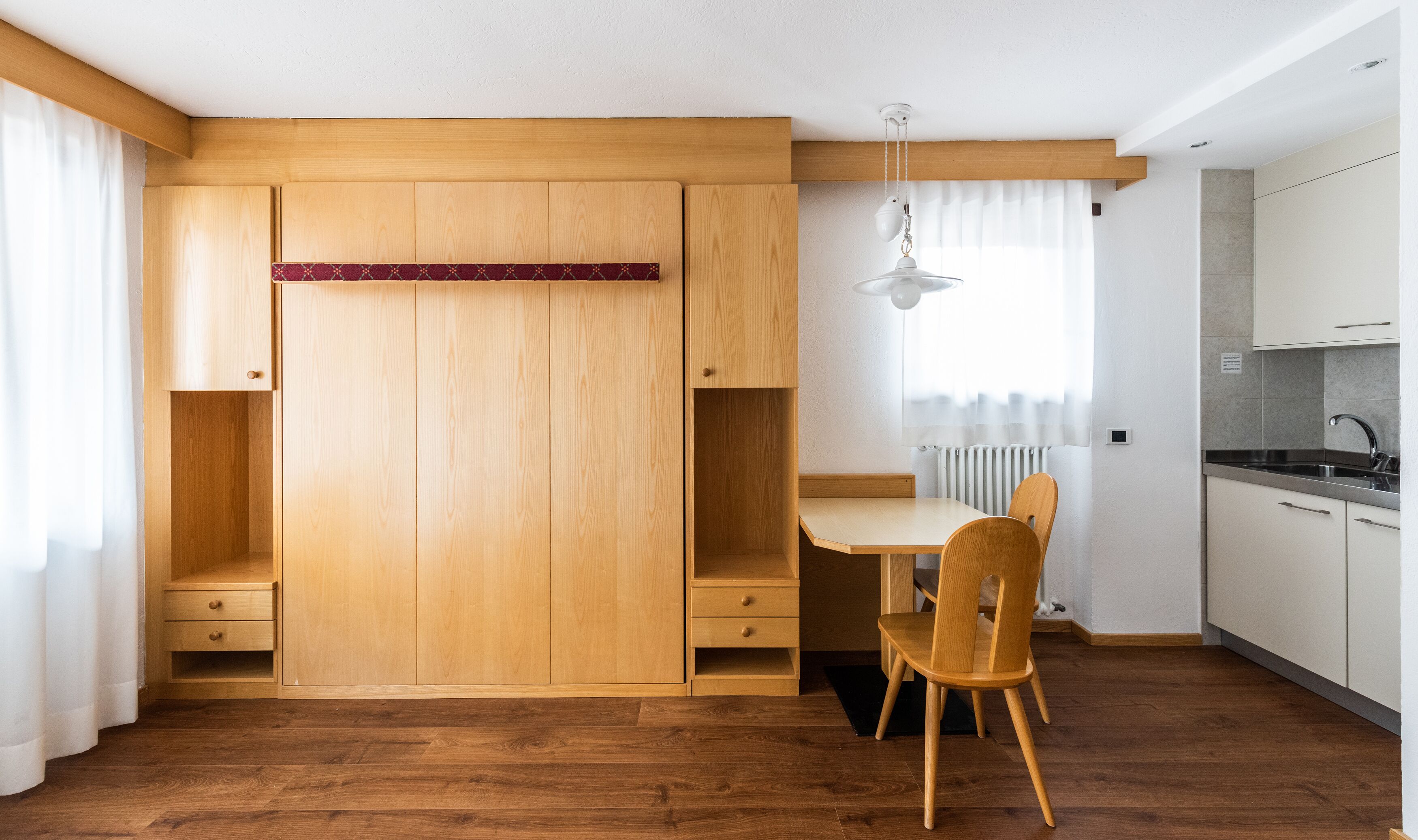 Una cocina compacta con armarios de madera, una mesa de comedor y una silla.