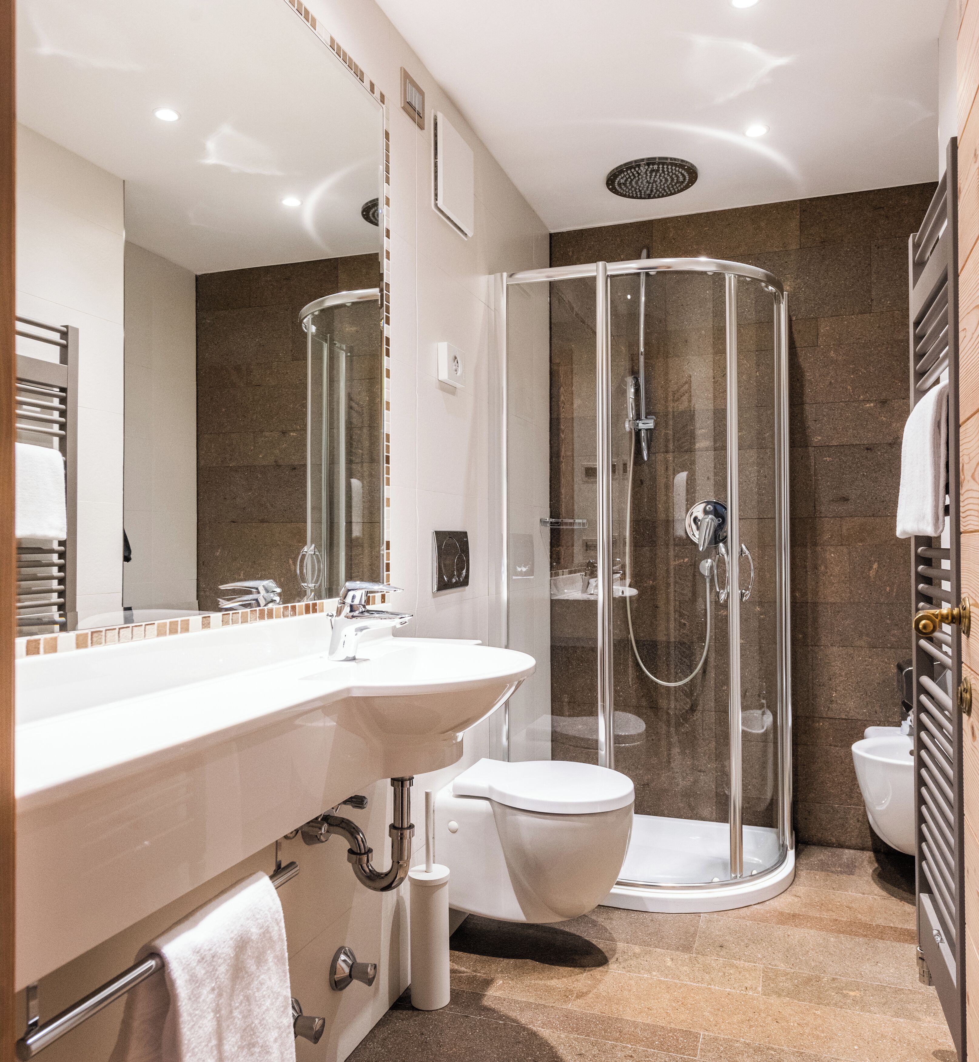 A modern bathroom with a glass-enclosed shower, a white sink, and a toilet.