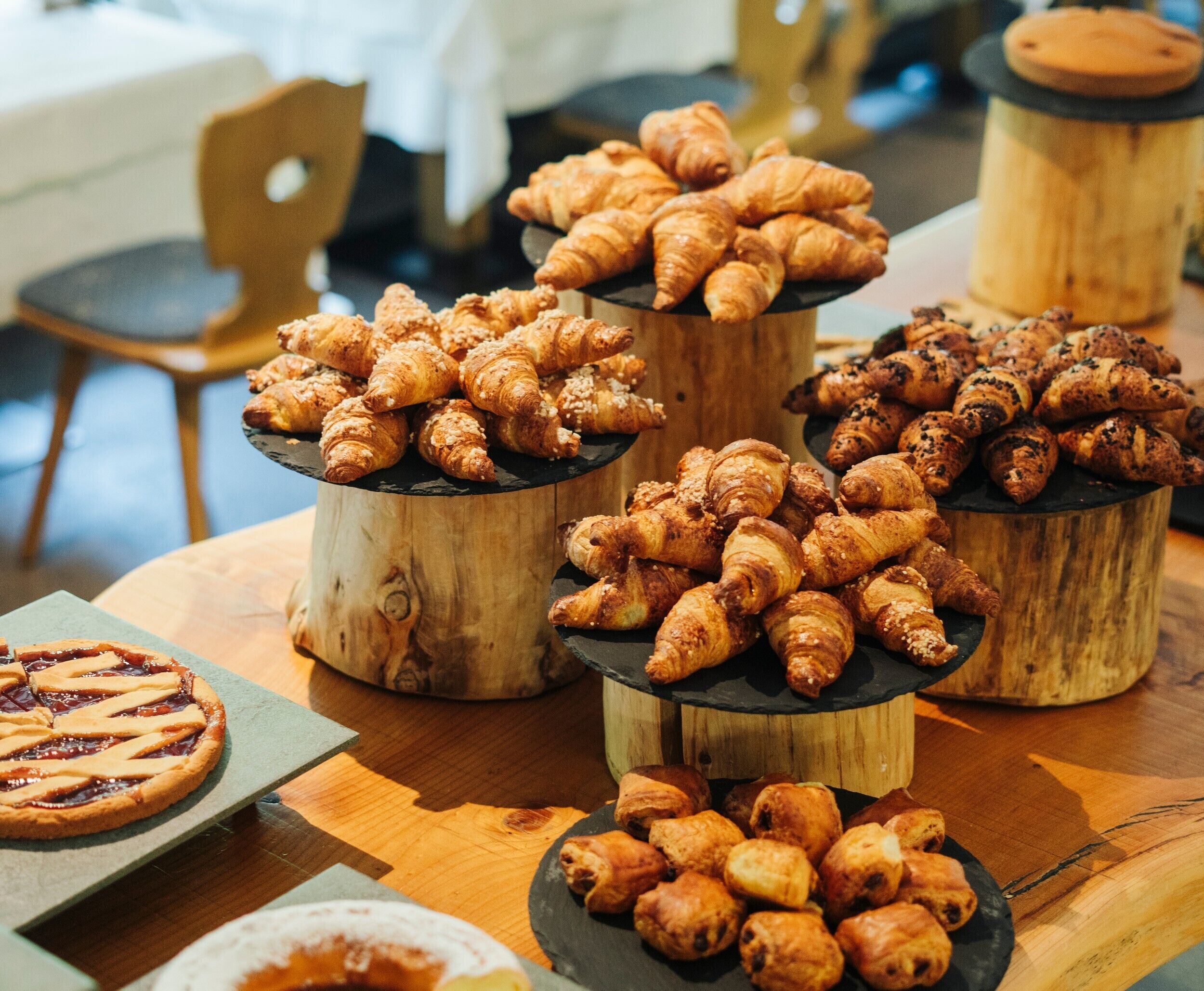 A table with various baked goods, including croissants and pastries, arranged on wooden stands.