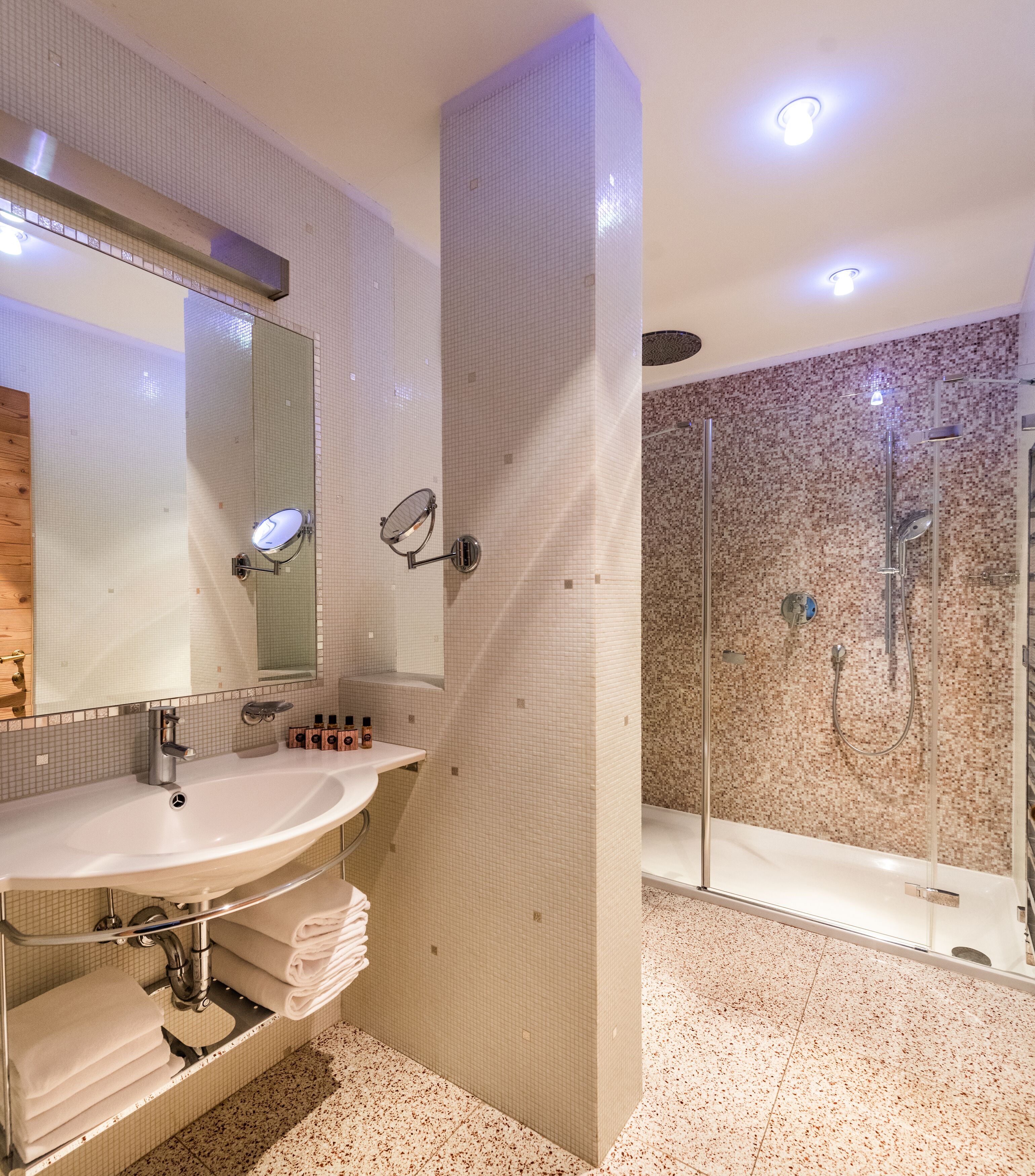 Un baño moderno con un espejo grande, dos lavamanos y una zona de ducha.