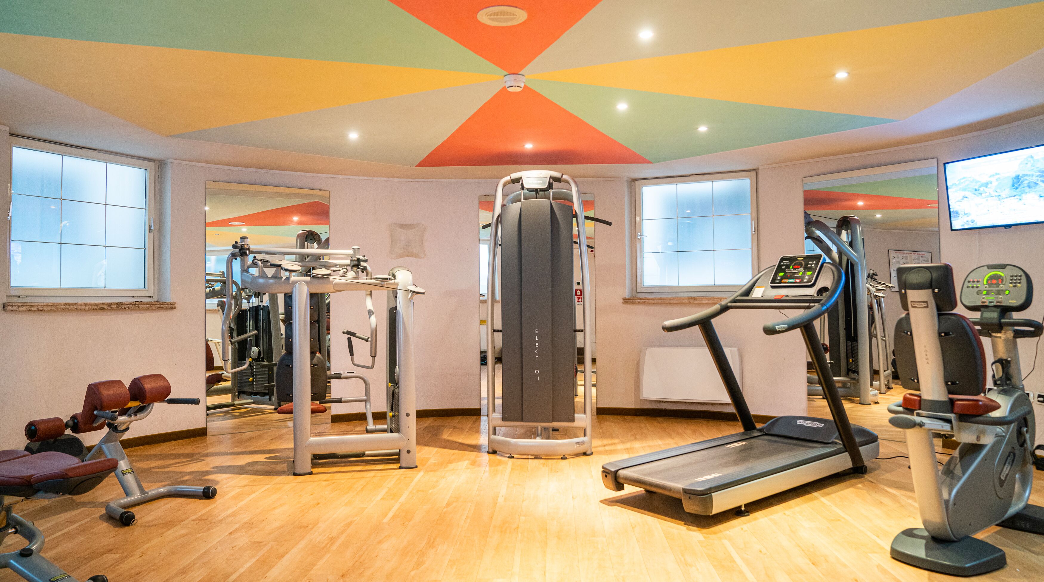 A gym with various exercise equipment, including a treadmill, weight machines, and a rowing machine.