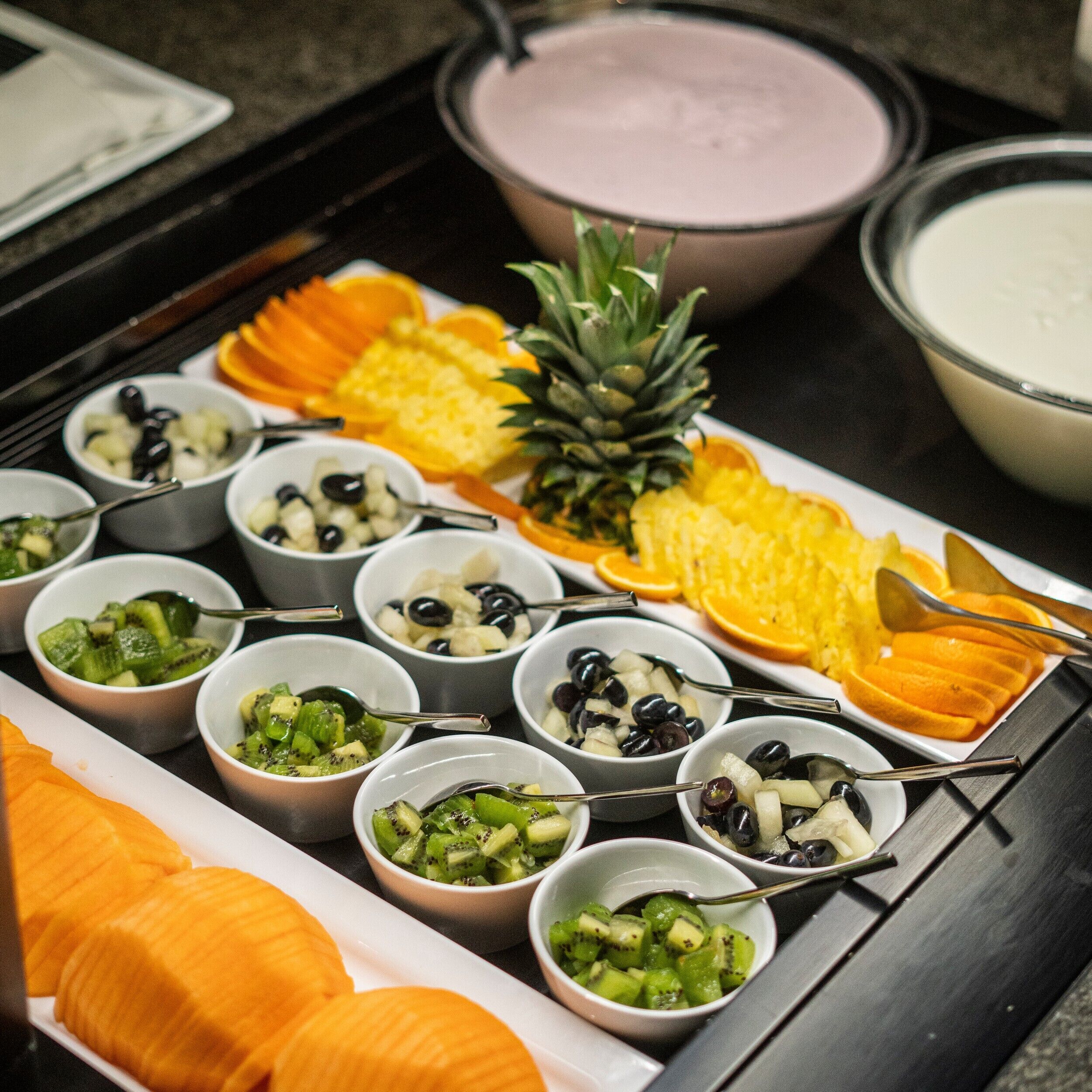 A buffet with various dishes including fruits, vegetables, and a pineapple centerpiece.