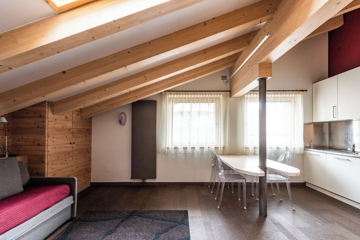 A loft-style room with a dining area, kitchen, and a sofa.