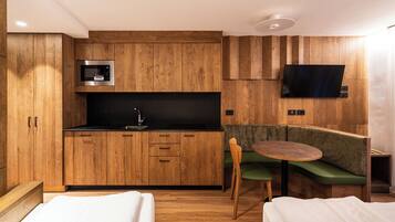 Une cuisine compacte avec des meubles en bois, un four à micro-ondes encastré, un évier et un téléviseur à écran plat fixé au mur.