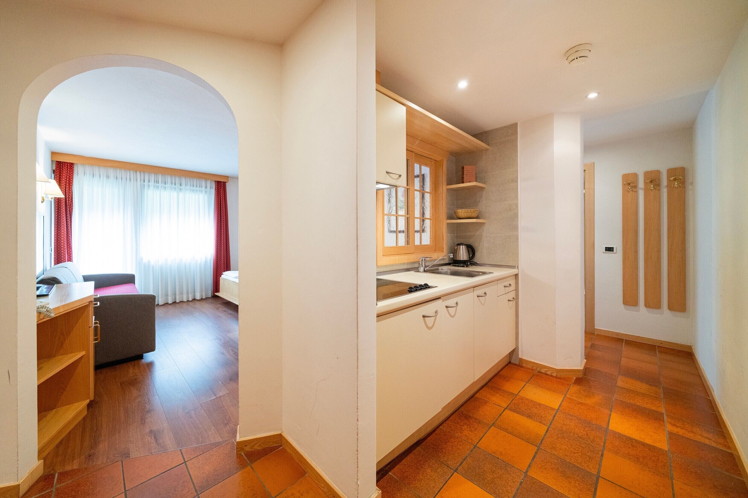 Una habitación de hotel moderna con kitchenette, zona de comedor y baño con armarios de madera.