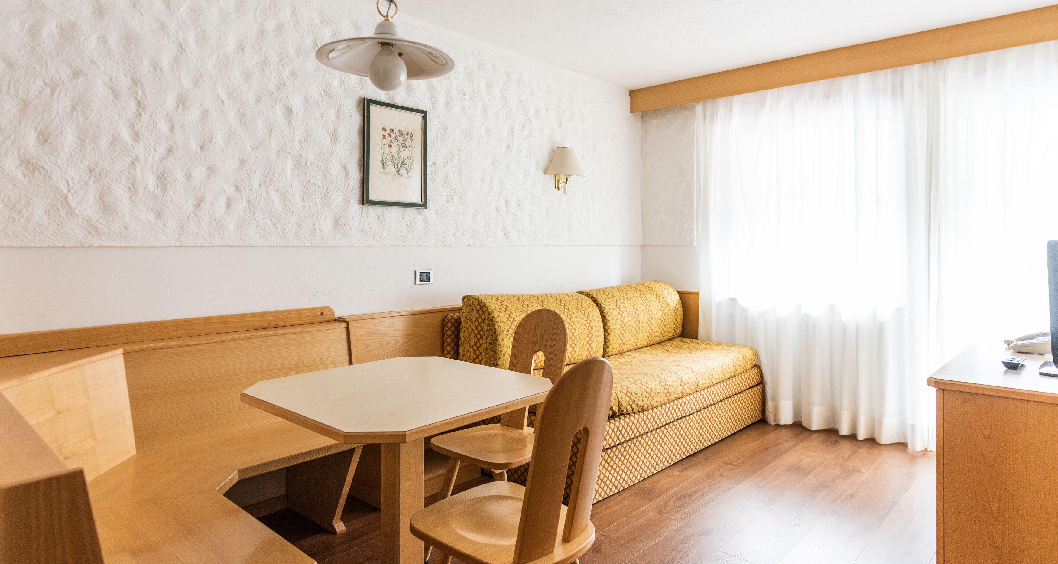 Una habitación con una mesa de madera, un sofá y una lámpara en la pared.