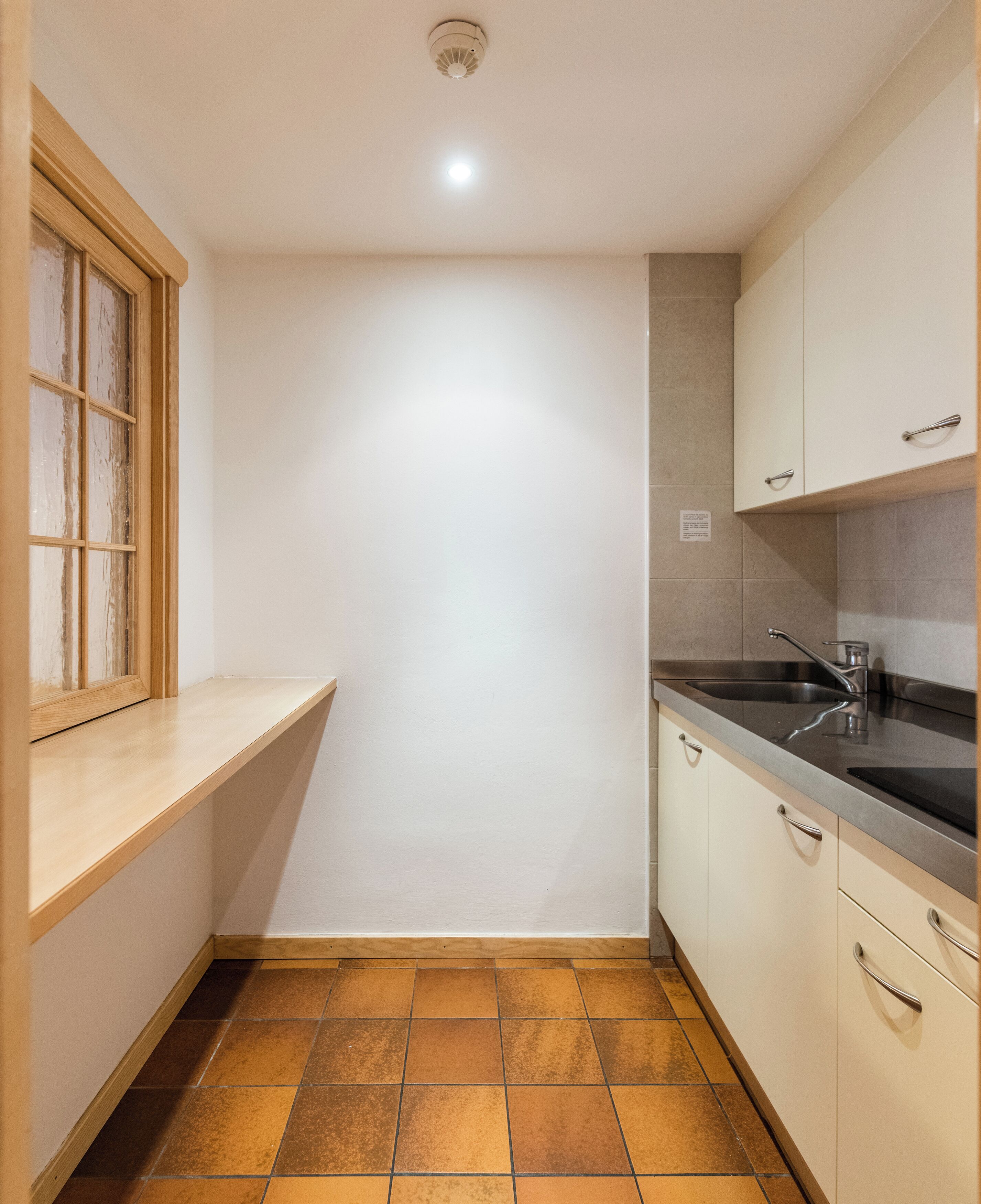 A small kitchen with a window, a sink, and cabinets.