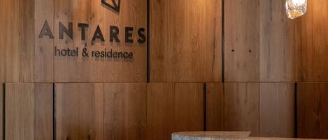 Un mostrador de recepción de madera con un logotipo y el nombre 'ANTARES hotel & residence'.