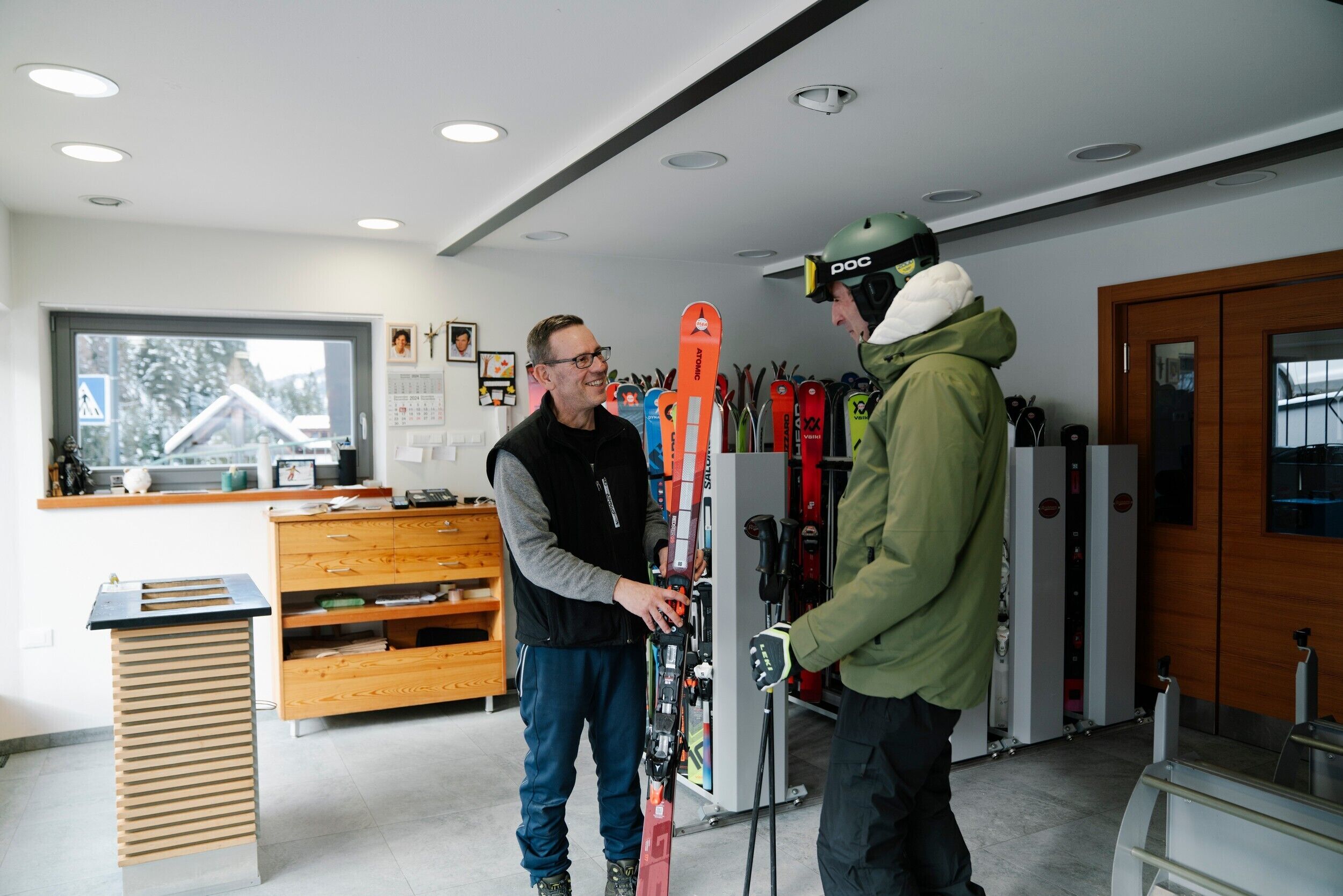 A ski rental shop interior with wooden cabinets, ski racks, and a wooden counter.