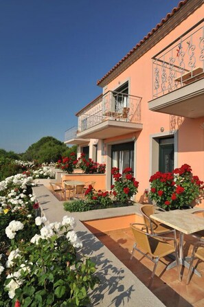 Un bâtiment à deux étages doté d’une terrasse et agrémenté de fleurs rouges.
