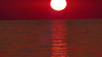 A sunset over a calm body of water with a reflection of the sun.