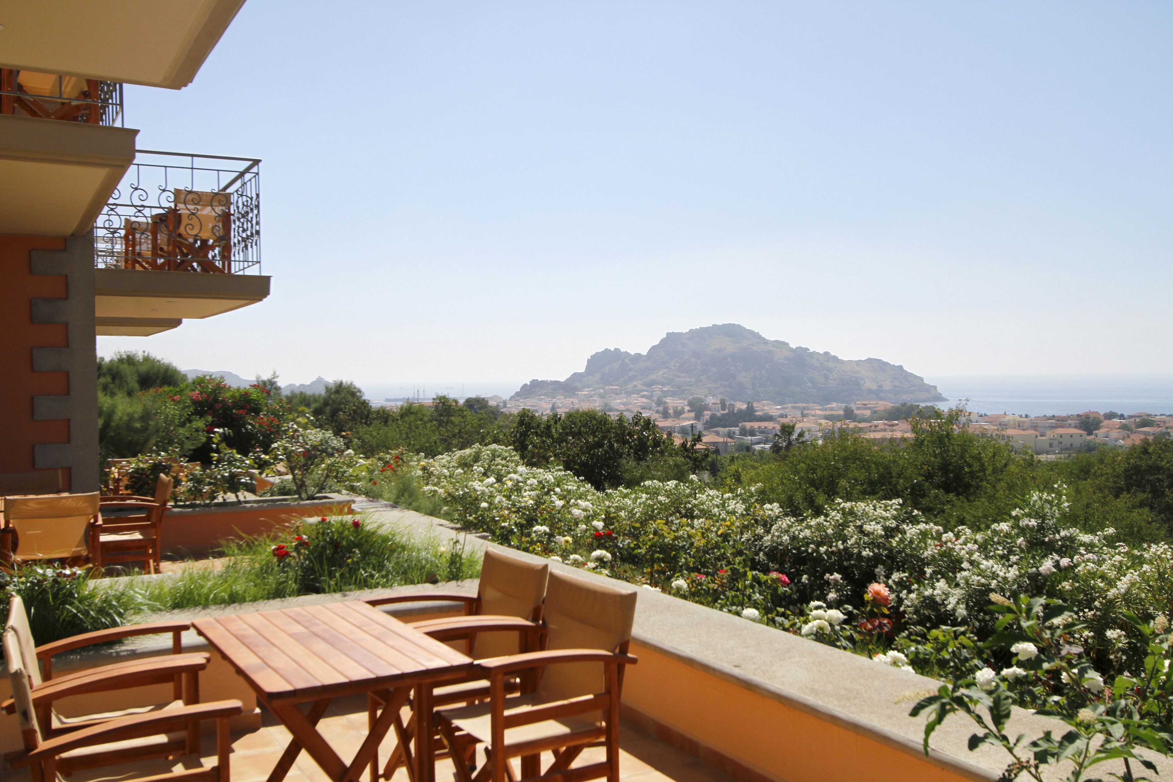 Una terraza con mobiliario de madera y vistas a la montaña y al pueblo.