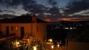 A building with a balcony and a garden at dusk. - Amygdalies Apartments (Lemnos)