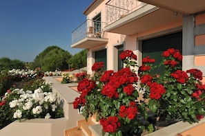 Un bâtiment doté d’un balcon, orné de fleurs rouges et blanches, avec un ciel dégagé.