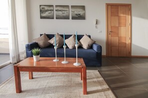 A living room with a blue sofa, three candles on a wooden table, and three paintings on the wall. - Ca Jasmine (Boa Vista)
