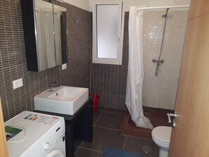 A bathroom with a white sink, a mirror, a shower with a white curtain, and a toilet. - Ca Jasmine (Boa Vista)