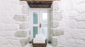 Un mur de pierres blanches avec une petite fenêtre et un panier rempli de serviettes.