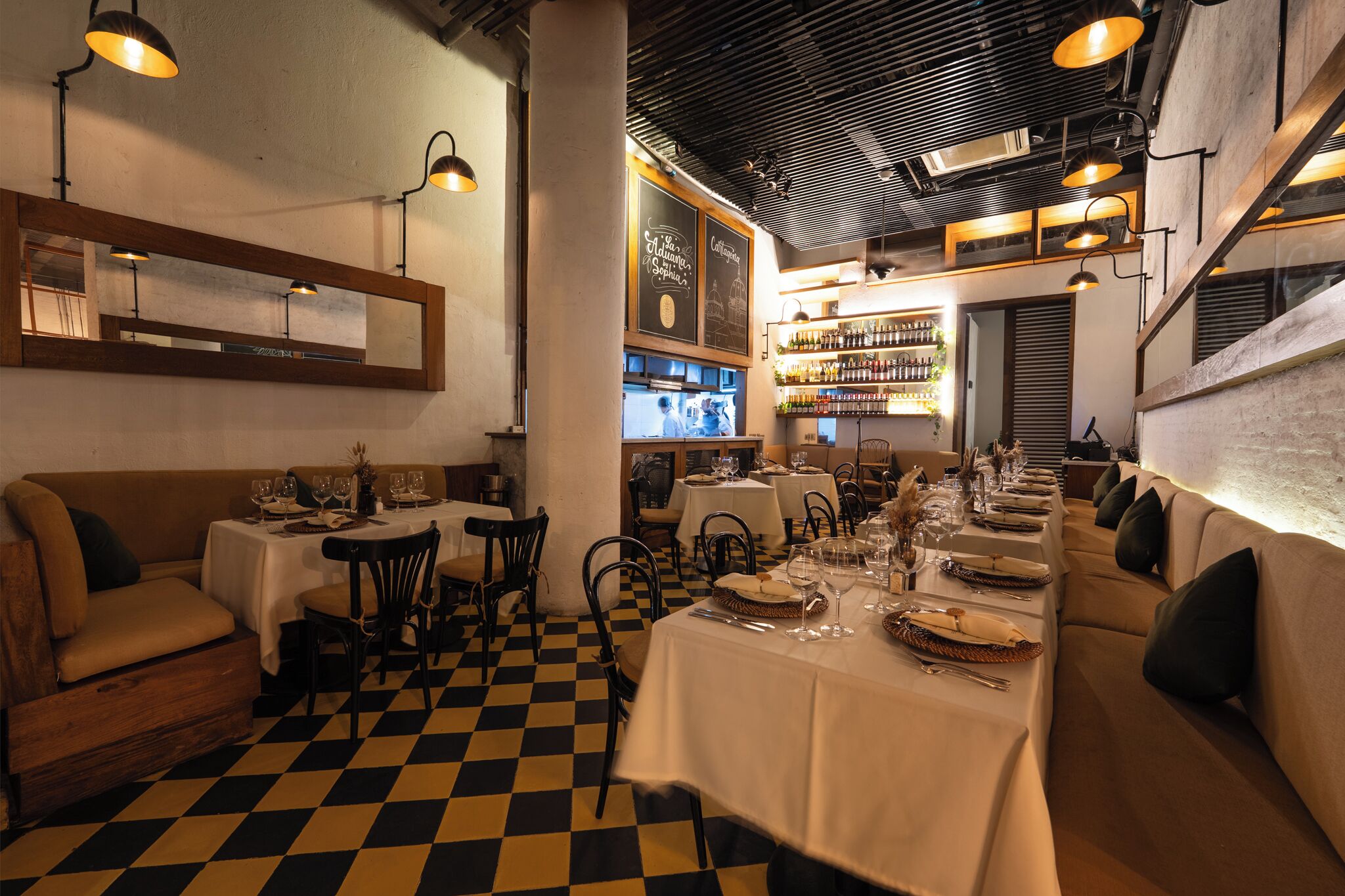 A restaurant with checkered flooring, tables set for dining, and a bar area in the background.