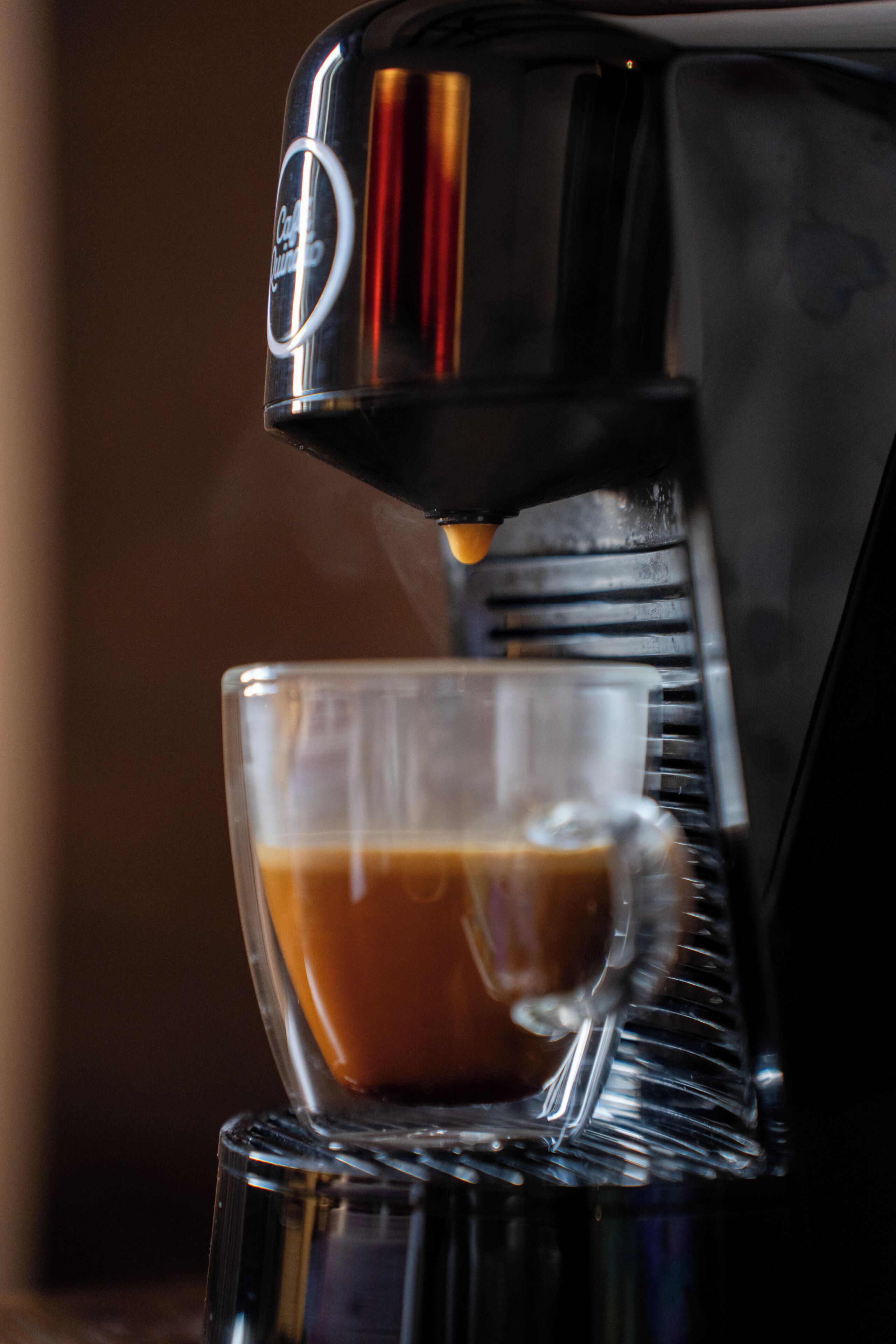 En kaffemaskin som häller kaffe i en glaskopp.