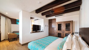 Una camera d'albergo con un letto, una televisione, un armadio in legno e una sedia in vimini.