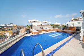 A rooftop swimming pool with lounge chairs and umbrellas, surrounded by buildings and a clear sky. - Sophia Hotel By OxoHotel (Cartagena)