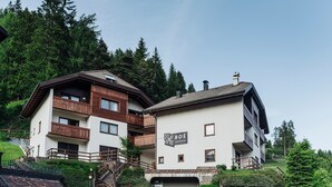 A two-story residential building with balconies, a sign reading "BOË apartments," and a mountainous backdrop.