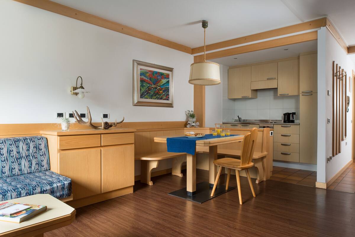 Een moderne keuken met houten kasten, een eettafel met stoelen en een bank.