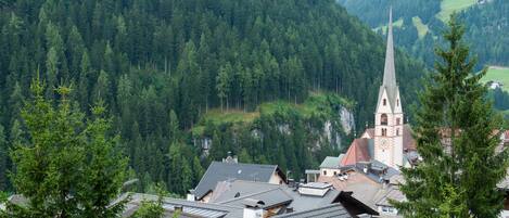 Une ville dont l’église, reconnaissable à son clocher imposant, est entourée d’une forêt dense et de montagnes.
