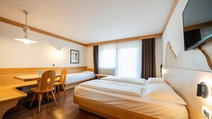Een hotelkamer met twee bedden, een bureau, stoelen, een flatscreen-tv en een raam met gordijnen.
