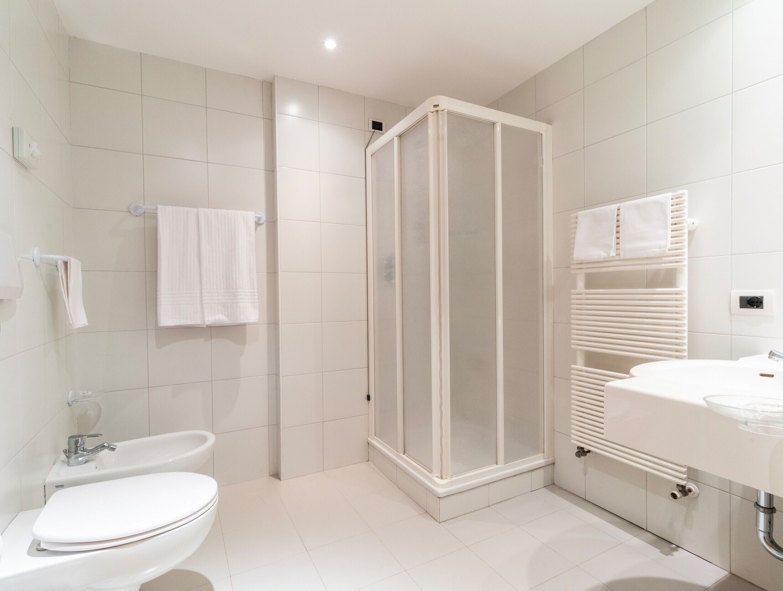 A modern bathroom with a shower enclosure, a toilet, and a sink.