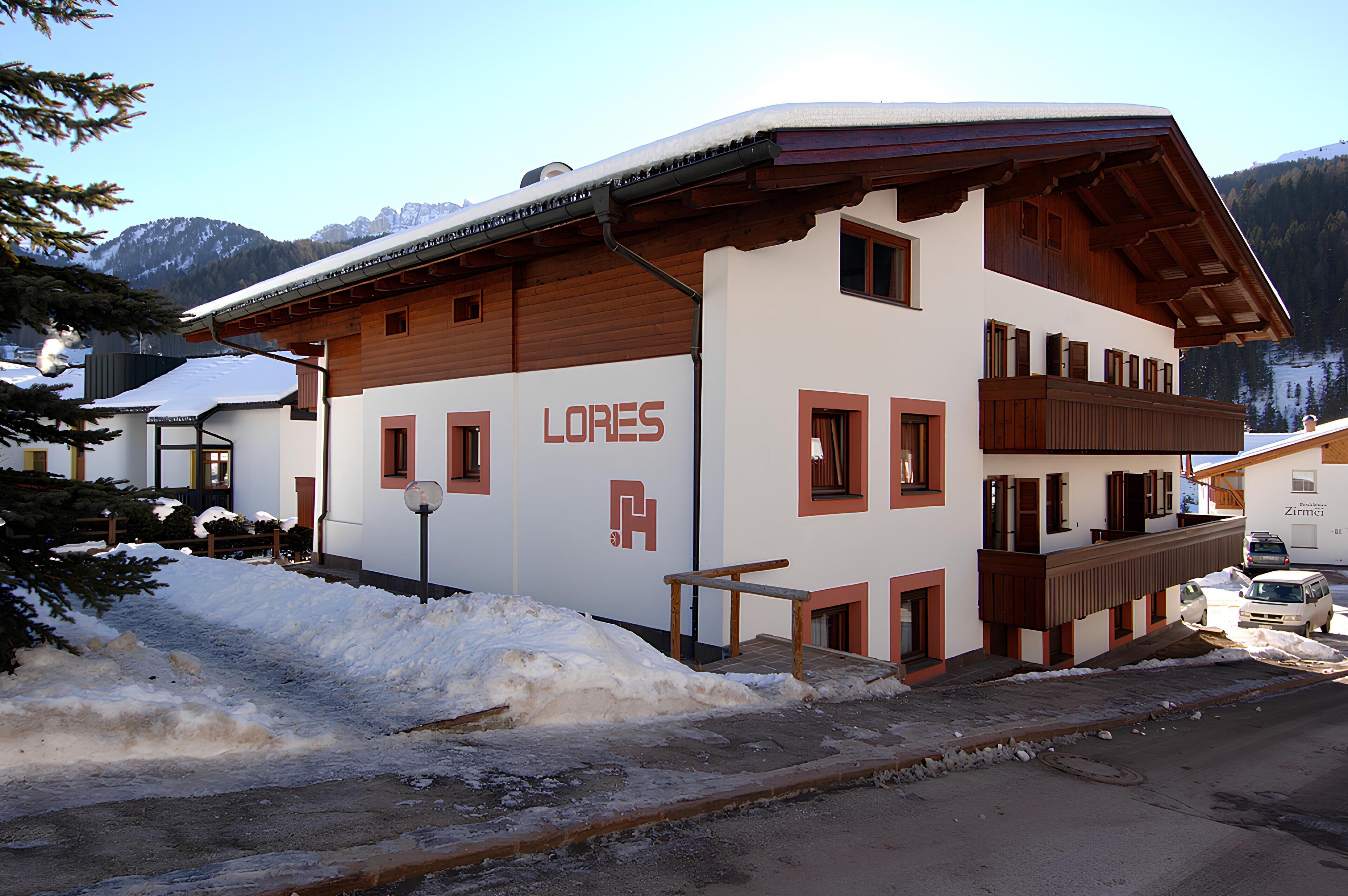 A white building with 'LORES' signage, wooden balconies, and a snow-covered landscape.