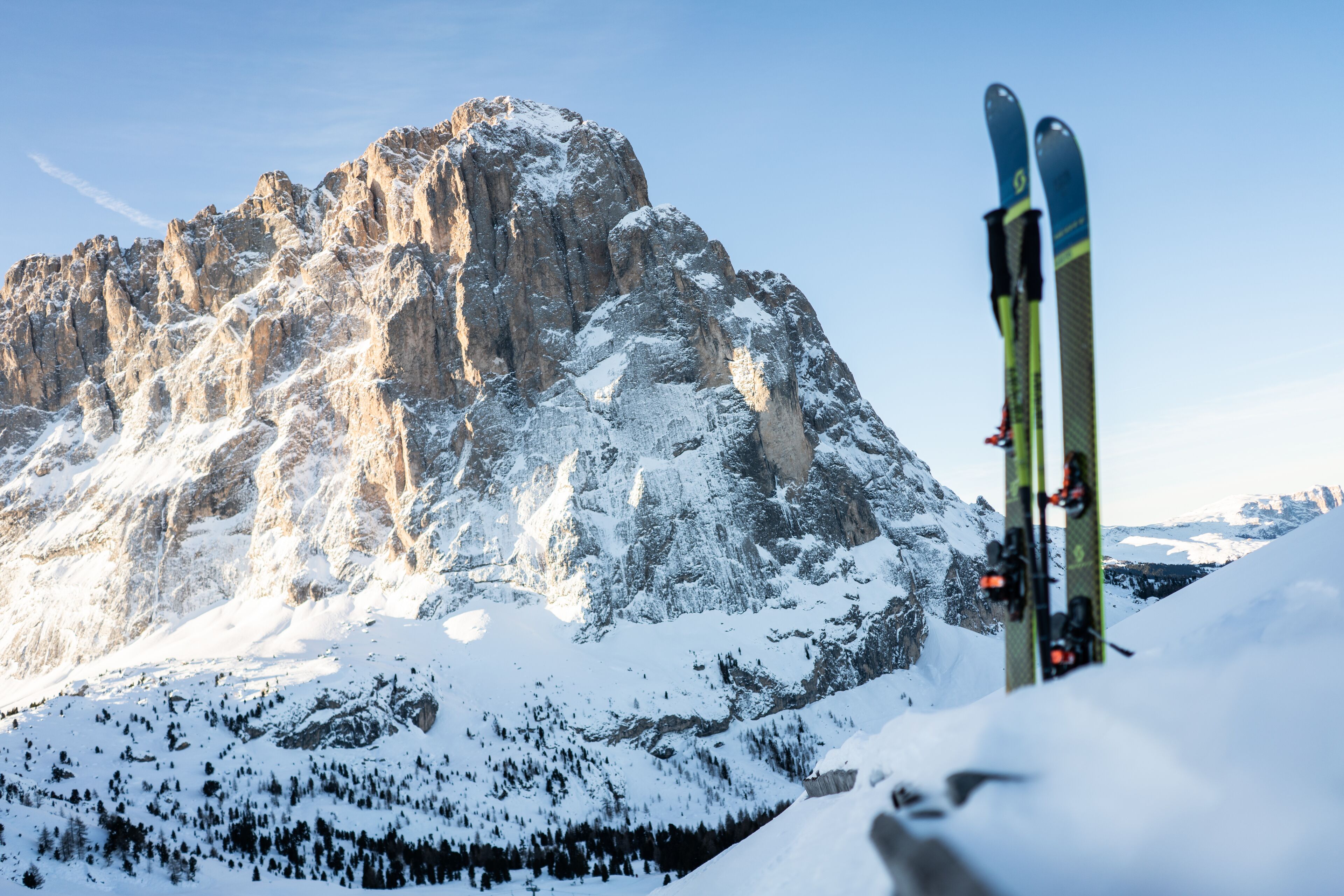 A mountain landscape with snow-covered peaks and a pair of skis leaning against the snow.