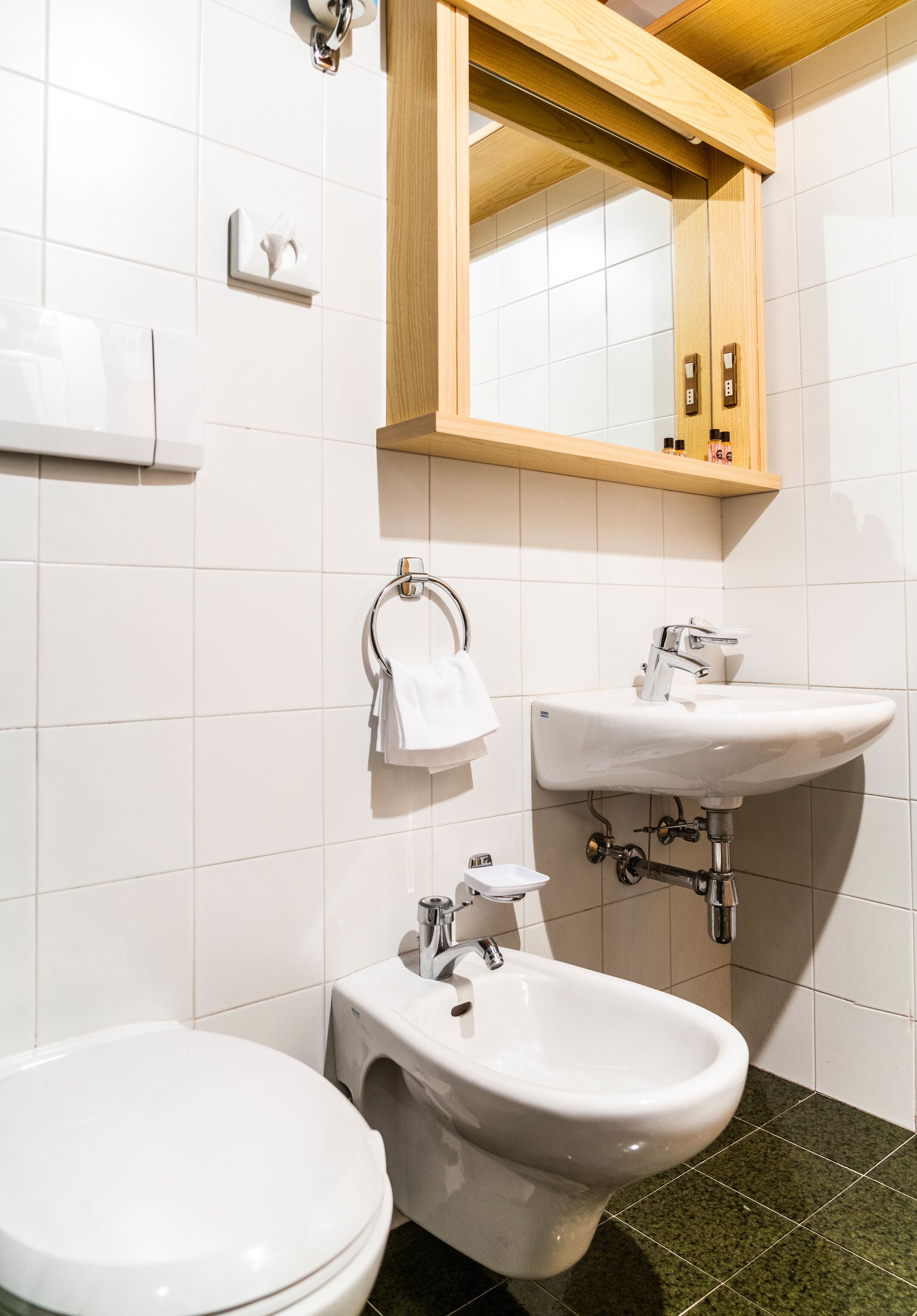 A modern bathroom with a toilet, bidet, and sink.