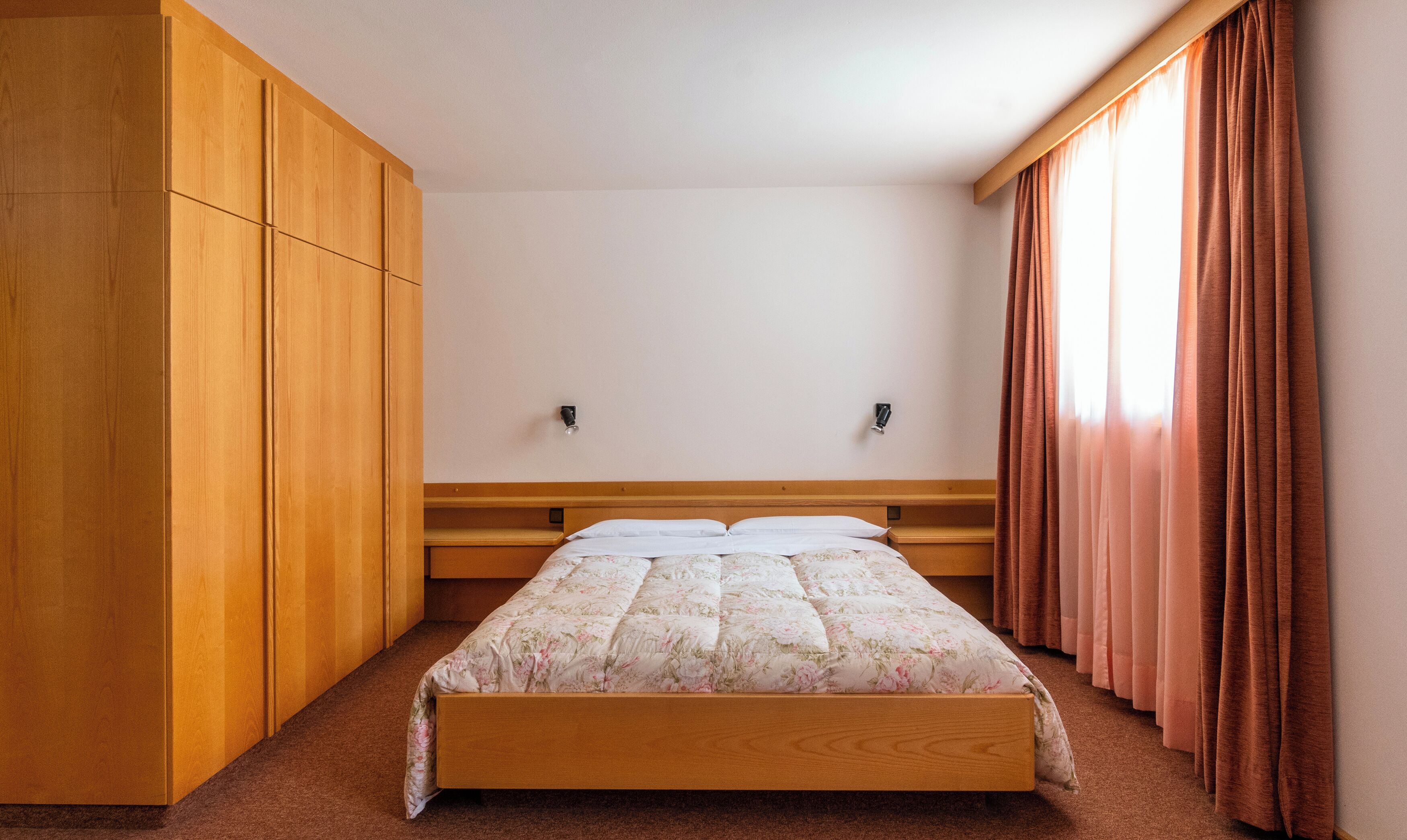 Une chambre à coucher avec un lit en bois, une armoire et des rideaux.