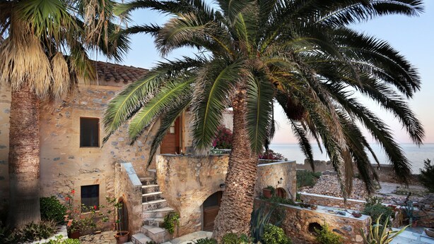 Ein Steinhof mit einer Treppe, die zu einem Balkon mit Blick auf einen Strand führt.