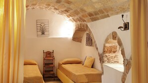 Ein gemütliches Zimmer mit zwei Betten, einem Holzstuhl und einer Steinwand.