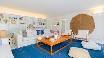 A modern living room with a white sofa, a wooden coffee table, and a large woven rug.