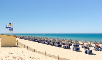 En la playa, sillas reclinables de playa, sombrillas, toallas de playa